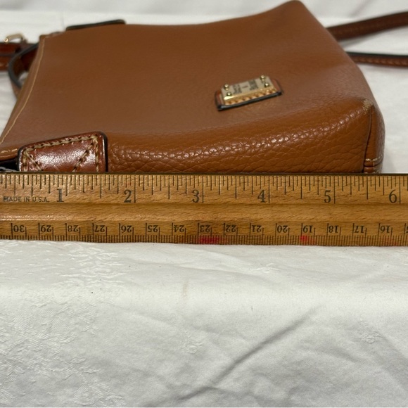 Dooney & Bourke Pebble Grain Crossbody Pouchette bag in a burnt orange color. - Picture 8 of 13